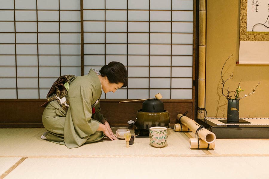 Tea master performing a Kyoto tea ceremony in a traditional tea room with garden view